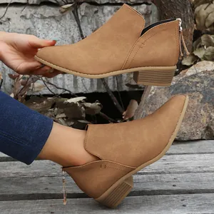 Detailopname van camel Chelsea boots met spitse neus, lage blokhak en rits achteraan