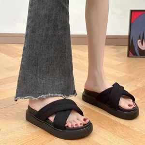 Detailed view of stylish black platform sandals with cross-straps worn by a model.