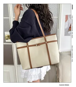 Minimalist cream faux leather tote bag with brown trim and buckle detail shown on shoulder