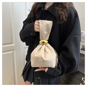 Detailed view of champagne pleated velvet bucket bag with gold metal ornament