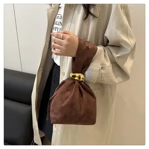 Detail showing the vintage brown suede bucket bag with a unique metallic gold-tone clasp.