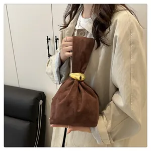 Close-up detail of a retro brown suede handbag with a unique gold-toned metal closure buckle