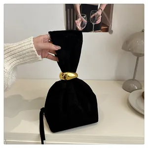 Close-up view of black velvet pouch bag with a decorative gold metal ring handle detail.