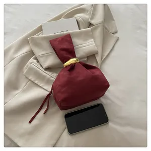 Macro view of burgundy velvet bucket bag with gold metal buckle detail