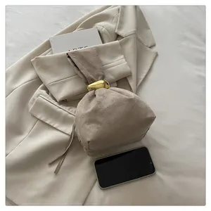 Close-up of vintage beige suede bucket bag with elegant gold metallic ring handle