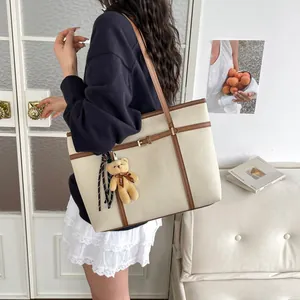 Minimalist cream tote bag with brown trim and cute teddy bear charm accessory