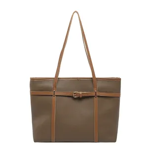 Minimalist textured brown women's tote bag with decorative buckle strap detail on white background