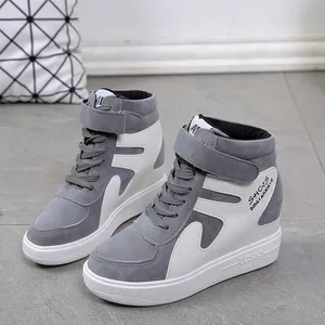 Détail latéral de baskets compensées en daim gris et blanc avec scratch.