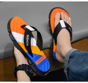 Close-up of men's vibrant orange and blue beach flip-flops with anti-slip rubber soles