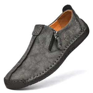 Primer plano de mocasines de cuero gris con cremallera y costuras hechas a mano.