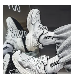 Close-up of white and silver chunky sneakers with mesh detail and striped laces.
