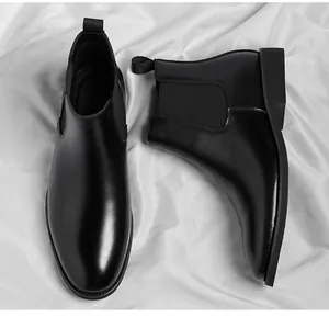Detail of black leather Chelsea boots showing sleek texture and elastic side panels.