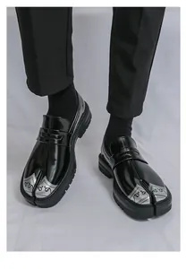 Detalle de mocasines negros con punta dividida para hombre y punteras plateadas