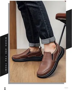 Detailaufnahme von braunen Echtleder-Slippern, getragen mit Denim-Jeans auf einem Holzboden