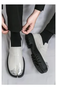Primer plano de mocasines Tabi blancos con punta dividida y suelas de tacos negras gruesas.