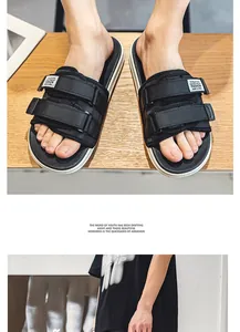 Close-up of men's black sports sandals with adjustable velcro straps on wooden floor