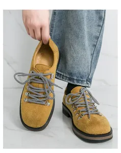Detailansicht der senfgelben Wildlederschuhe mit gestreiften Schnürsenkeln und Ösen.