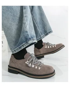 Braune Herrenschuhe aus Wildleder im britischen Stil mit Schnürung vor Marmorhintergrund.