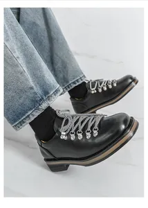 Detail der schwarzen Herren-Lederschuhe im britischen Stil mit Metallösen und Schnürung.