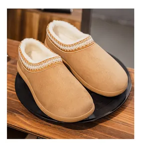 Gros plan de chaussons en daim marron avec doublure polaire et broderie ethnique.