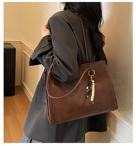 Elegant large brown leather tote bag with bead charm accessory worn by a model