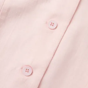 Close-up of pink fabric texture and matching buttons on a sweet vest set