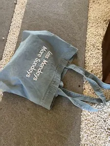 High-quality detail of light blue canvas tote bag featuring white printed text detail