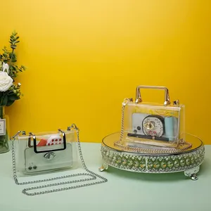 Two transparent PVC clutches with gold chain straps in a decorative studio setting