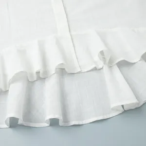 Gros plan détaillé montrant le tissu texturé et l'ourlet à volants d'un chemisier d'été