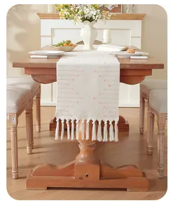 Chemin de table blanc à pois roses et pompons élégants dans un cadre chaleureux et convivial.