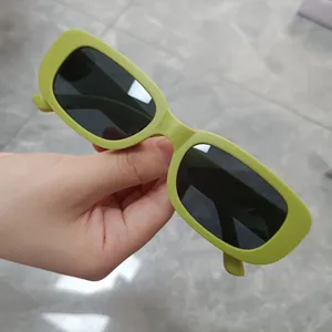 Macro detail view of trendy lime green rectangular sunglasses featuring dark tinted lenses