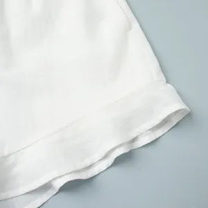 Gros plan de l'élégant ourlet à volants blancs sur un short d'été en lin respirant.