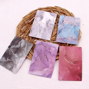 Collection of marble gilt jewelry display cards for earrings and necklaces in various colors.