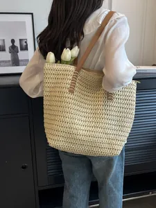 Detailed shot of a woven straw tote bag over the shoulder accessorized with white tulips