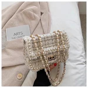 Detailed view of an elegant white tweed crossbody bag with pearl trim and chain