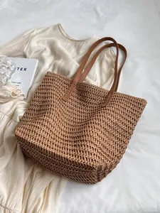 Handmade woven straw tote bag for summer beach travel on white fabric background