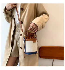 Lifestyle shot of a stylish canvas and leather bucket bag carried by a fashion model