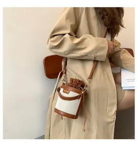 Detailed macro shot of a stylish canvas bucket bag featuring premium brown leather trim and drawstring