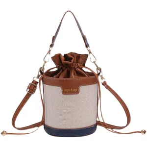 Stylish women's canvas bucket bag with brown leather trim and adjustable crossbody strap