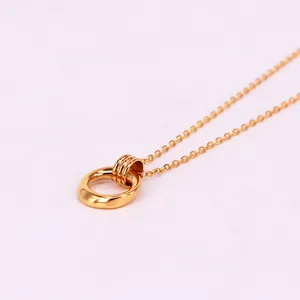 Gros plan d'un collier en acier titane doré avec pendentif double anneau et fini lisse