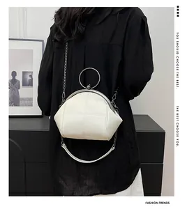 Vue détaillée du sac coquillage blanc avec poignée en métal et bandoulière chaîne