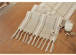 Detailed macro view of bohemian cotton linen table runner featuring embroidery and tassels