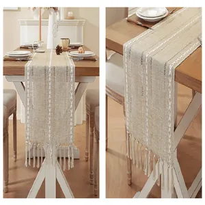 Close-up detail of a beige cotton linen table runner with white embroidery and tassels.