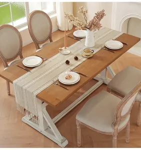 Detail of handmade linen table runner with white embroidery and fringe accents