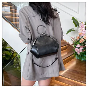 Sac vintage noir avec poignée en métal et bandoulière en chaîne porté par un mannequin