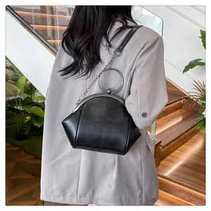 Sac à main vintage noir avec poignée ronde en métal et bandoulière chaîne porté par modèle