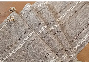 Detailed macro view of a rustic linen table runner with white embroidery patterns