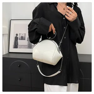 Sac à bandoulière blanc en forme de coquille avec poignée ronde argentée et chaîne.