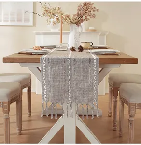 Close-up of rustic cotton linen table runner with handmade fringe tassels on a wooden table