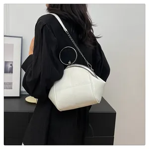Élégant sac à main blanc avec poignée en métal et bandoulière chaîne porté par un mannequin